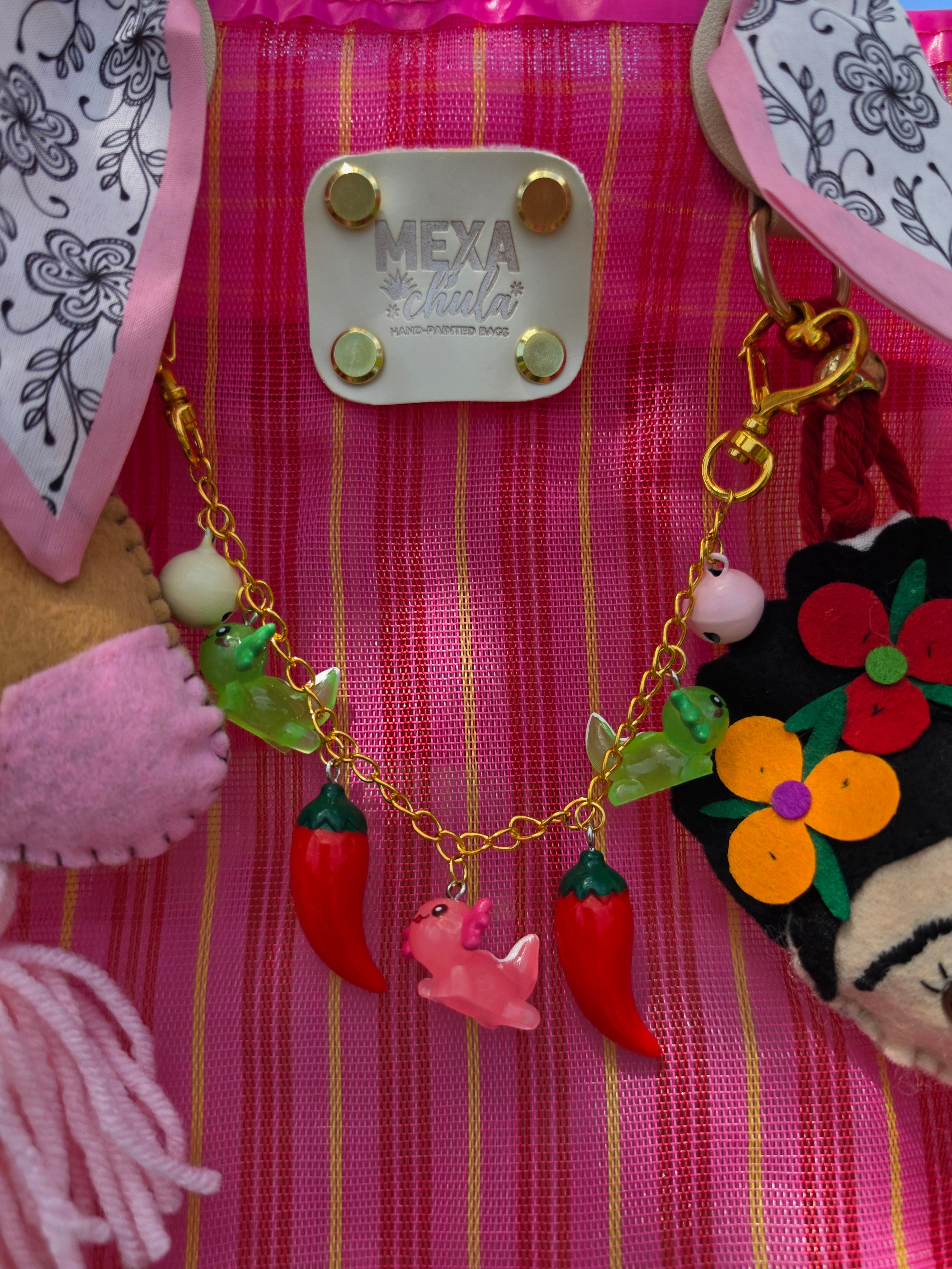 Cadena con charms de chiles, ranitas y dragoncito rosa en bolsa mexicana