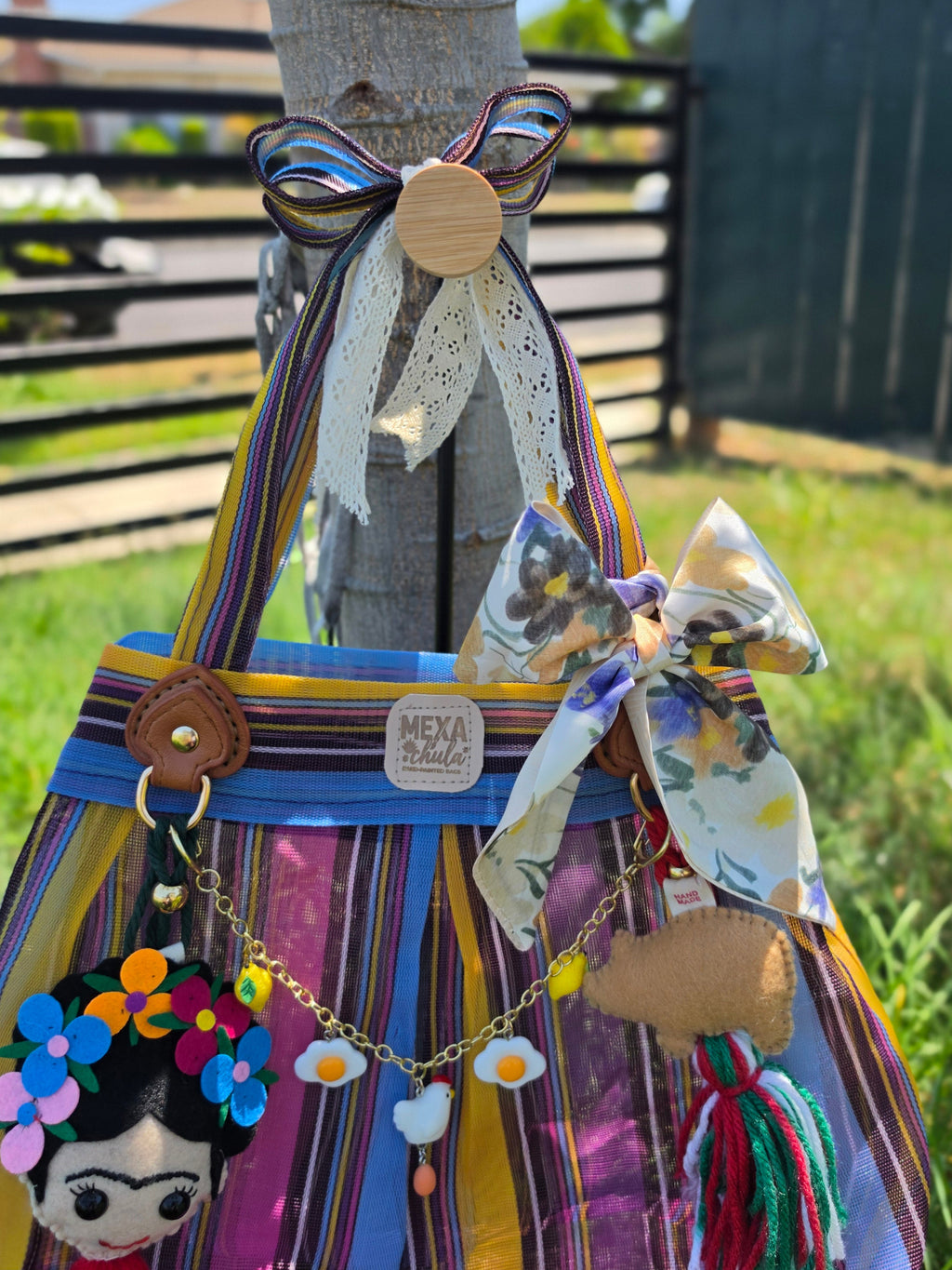 Detalle del charm de Frida con corona de flores de colores y cadena de dijes de huevos y gallina