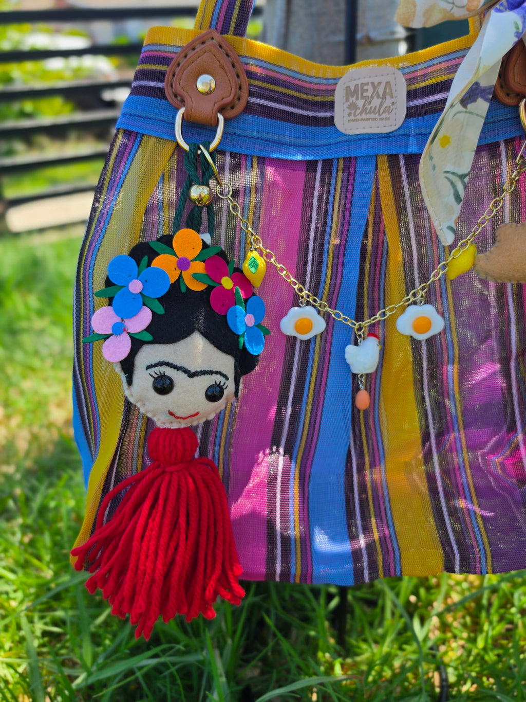 Detalle del moño floral con charm de cerdito y cadena de dijes de huevo en bolsa de mercado mexicana
