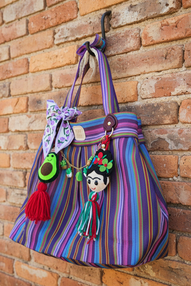 Bolsa de mercado mexicana de rayas multicolor con charm de Frida Kahlo de fieltro y borla tricolor, colgada al aire libre