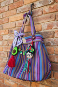 Bolsa de mercado mexicana de rayas multicolor con charm de Frida Kahlo de fieltro y borla tricolor, colgada al aire libre