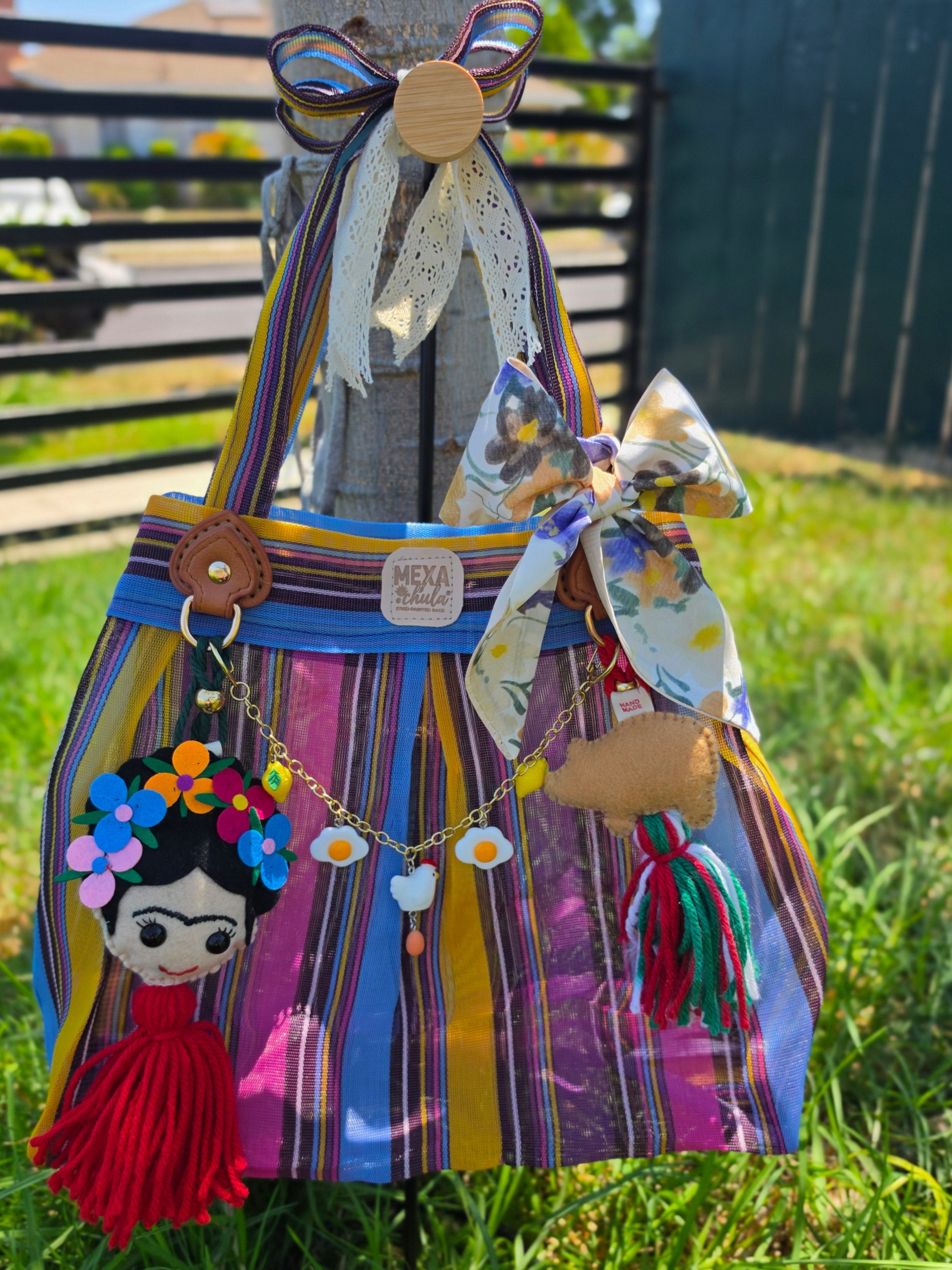 Vista frontal de bolsa de mercado mexicana con charms de Frida y cerdito y cadena de dijes de granja