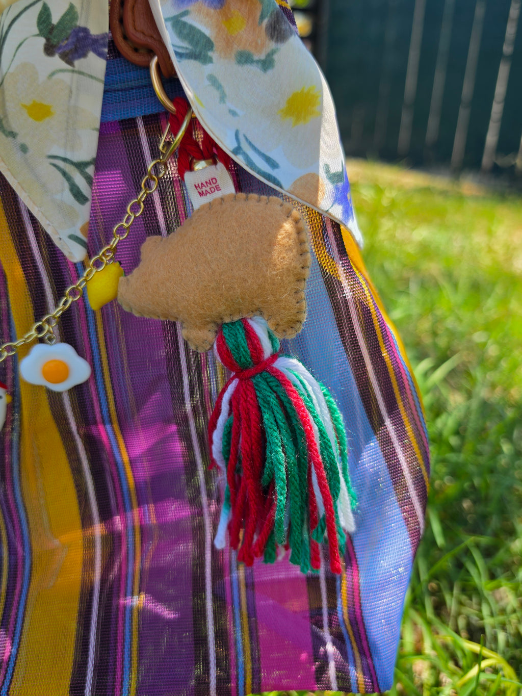 Charm de cerdito de fieltro con borla tricolor y moño floral amarillo en bolsa de mercado mexicana