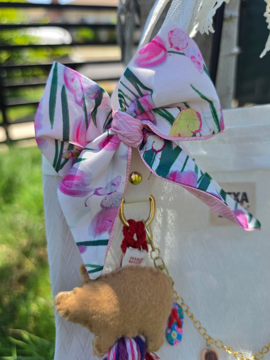 Detalle del moño floral rosa y charm de cerdita de fieltro en bolso de mercado mexicano color blanco