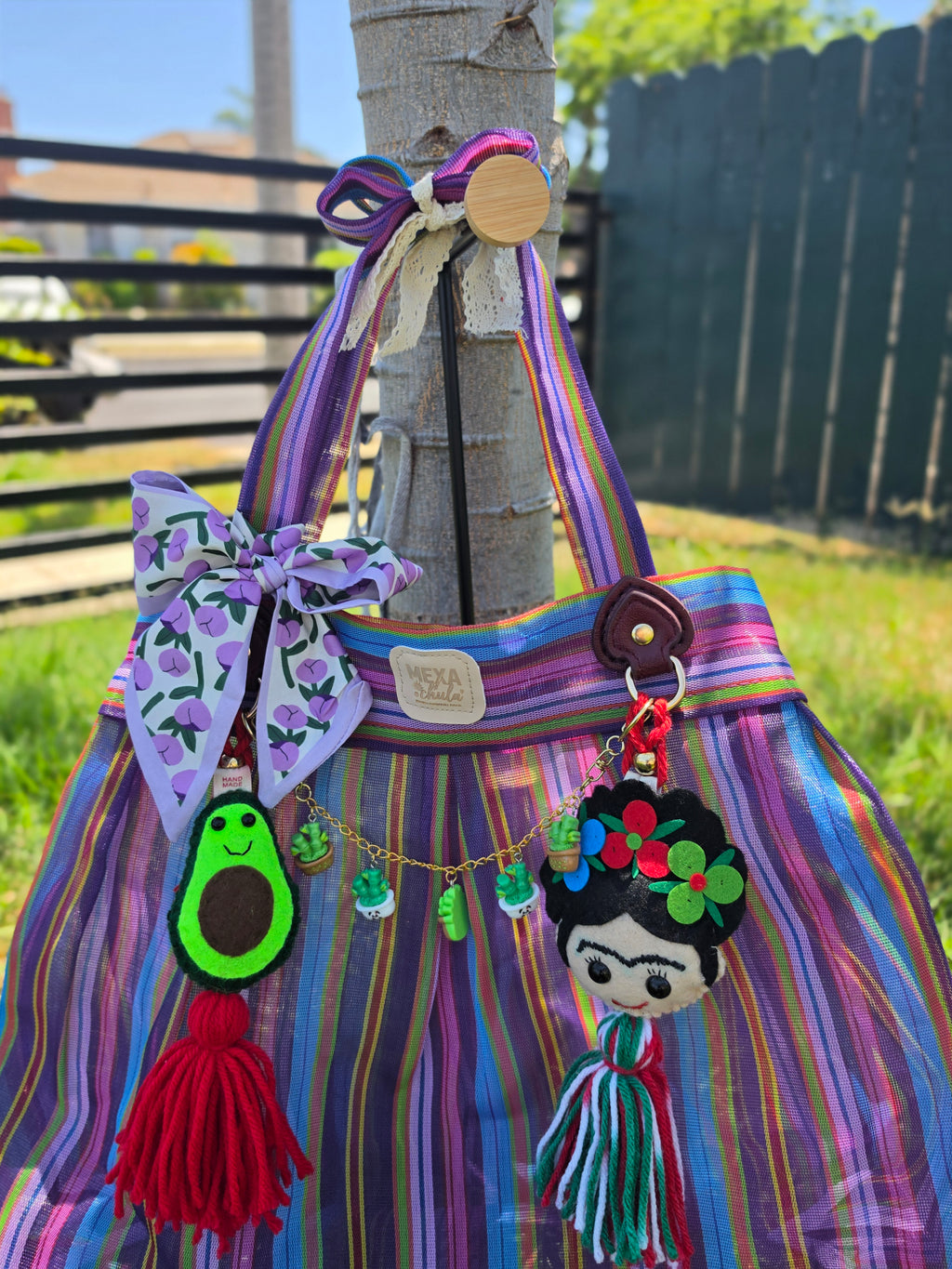 Vista frontal de bolsa de mercado mexicana artesanal con charms hechos a mano de aguacate y Frida Kahlo