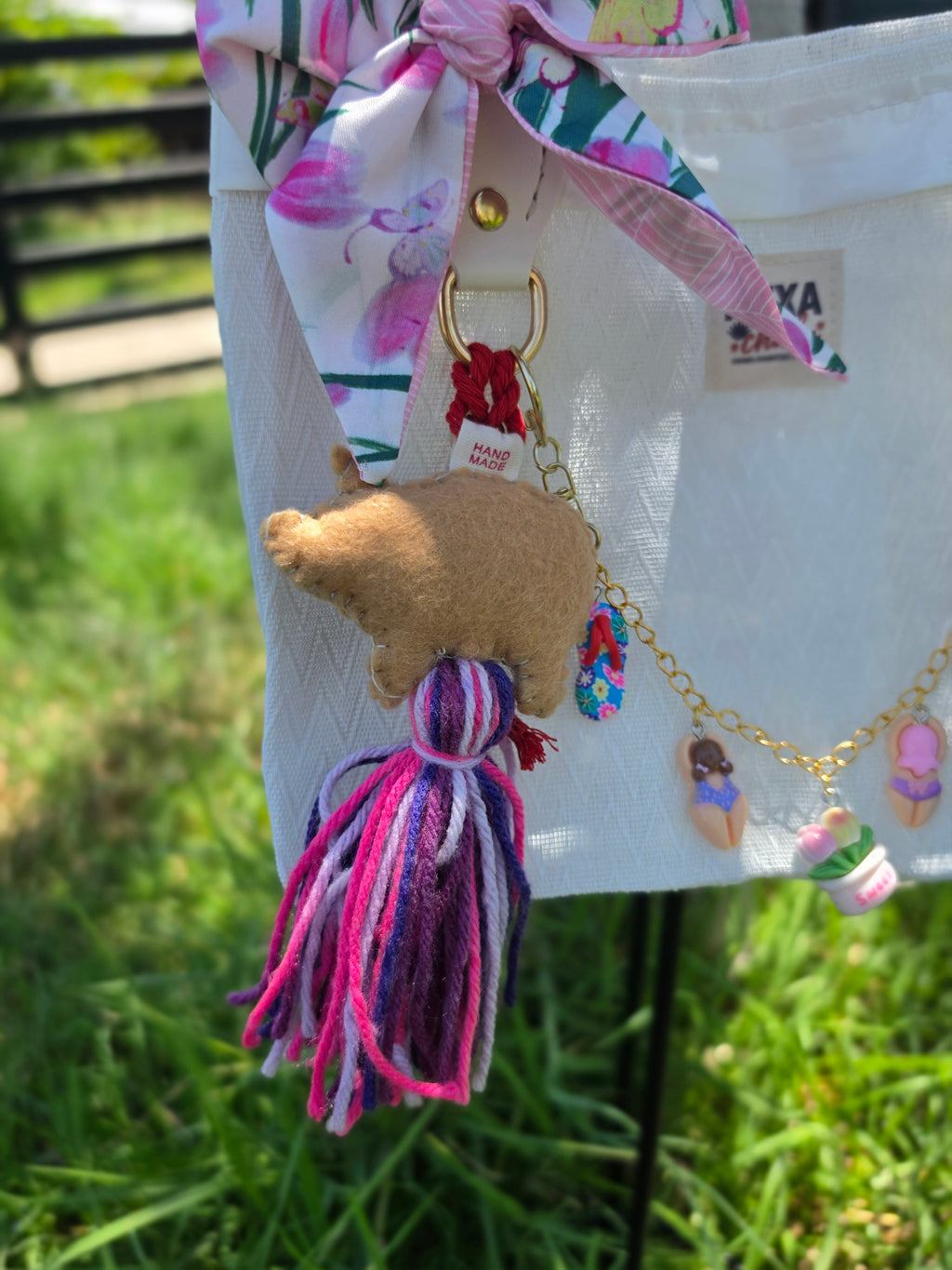 Detalle del moño floral rosa y charm de cerdita de fieltro en bolso de mercado mexicano color blanco