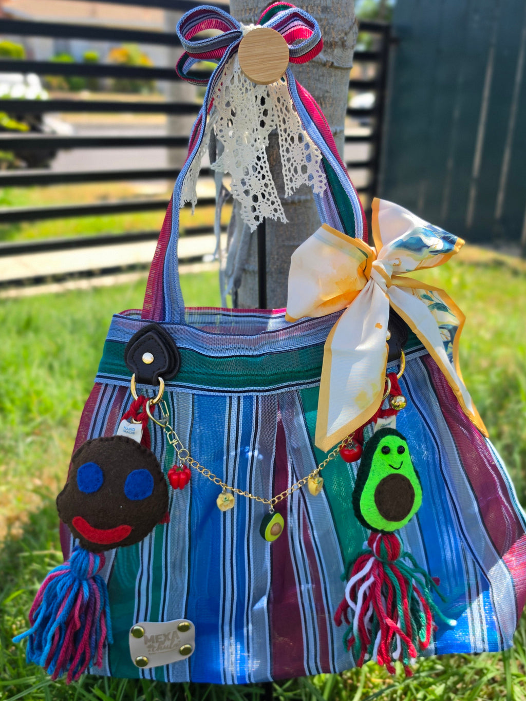Bolsa de mercado mexicana de rayas azul, verde y morado con set completo de charms colgada de un árbol