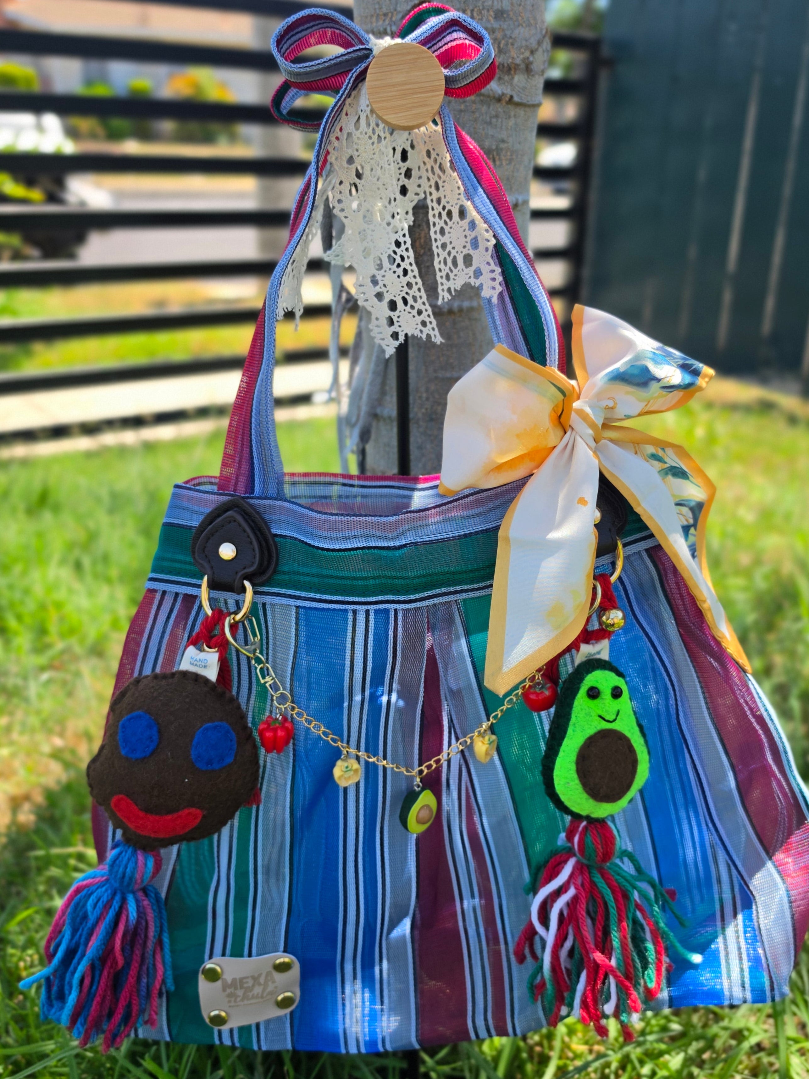 Bolsa de mercado mexicana de rayas azul, verde y morado con set completo de charms colgada de un árbol