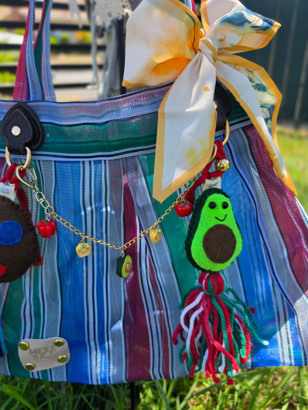 Vista frontal de bolsa de mercado mexicana con charms de carita sonriente y aguacate hechos a mano